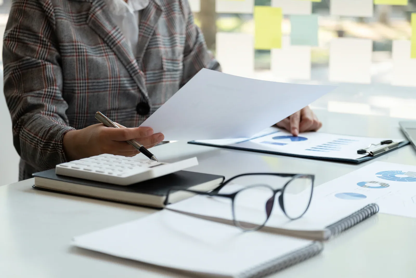 Manos de una profesional revisando informes financieros y una calculadora
