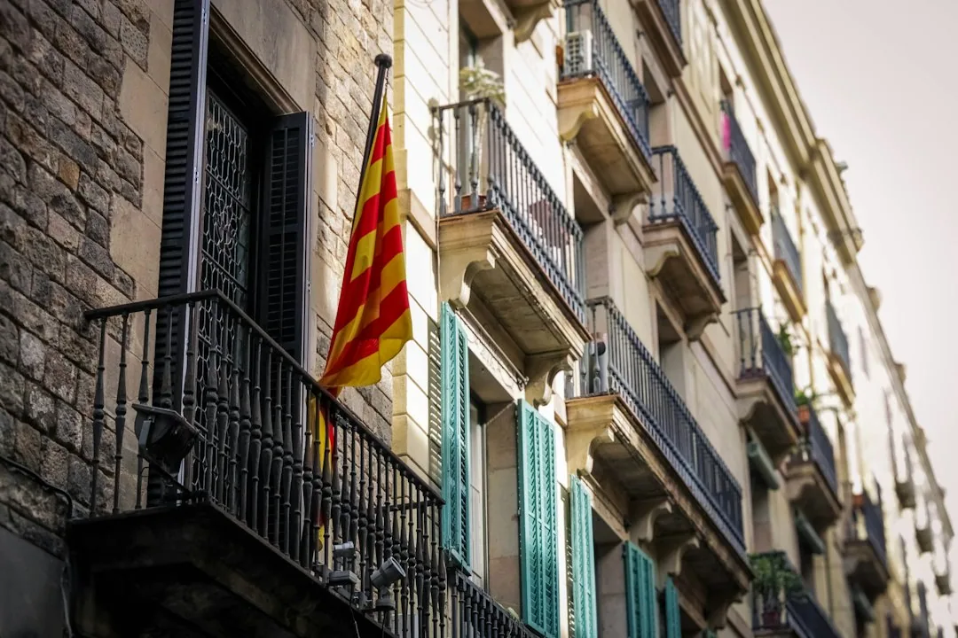 Balcón con bandera catalana en Barcelona, símbolo del contexto fiscal al donar un inmueble a hijos en Cataluña con Barcelona Tributario